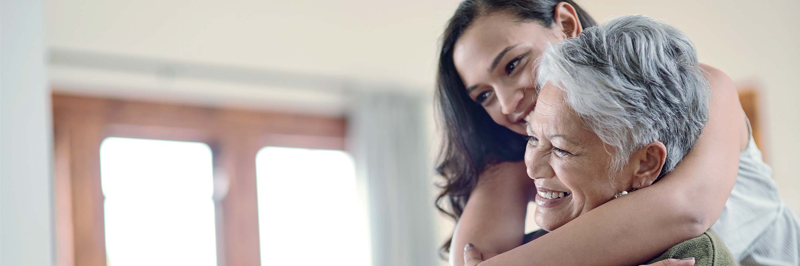 Femme qui enlâce une femme plus âgée qui souris